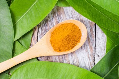 Tahta zemin üzerinde okaliptüs yaprakları ile kaşık içinde zerdeçal tozu