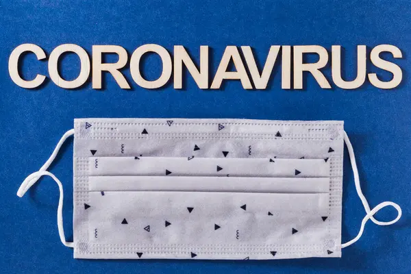 Coronavirus Wort Mit Holzbuchstaben Und Gesichtsschutzmaske Auf Blauem Hintergrund — Stockfoto