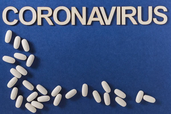Coronavirus Wort Mit Holzbuchstaben Und Komprimierten Medikamententabletten Auf Blauem Hintergrund — Stockfoto