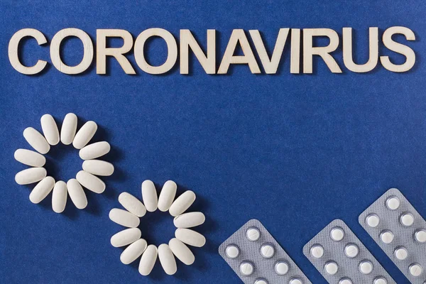 Coronavirus Wort Mit Holzbuchstaben Und Komprimierten Medikamententabletten Auf Blauem Hintergrund — Stockfoto