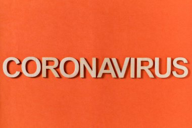 Turuncu arka planda ahşap harflerle Coronavirus kelimesi.
