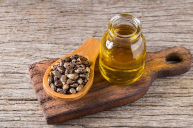 castor oil and seeds, on wooden background clipart