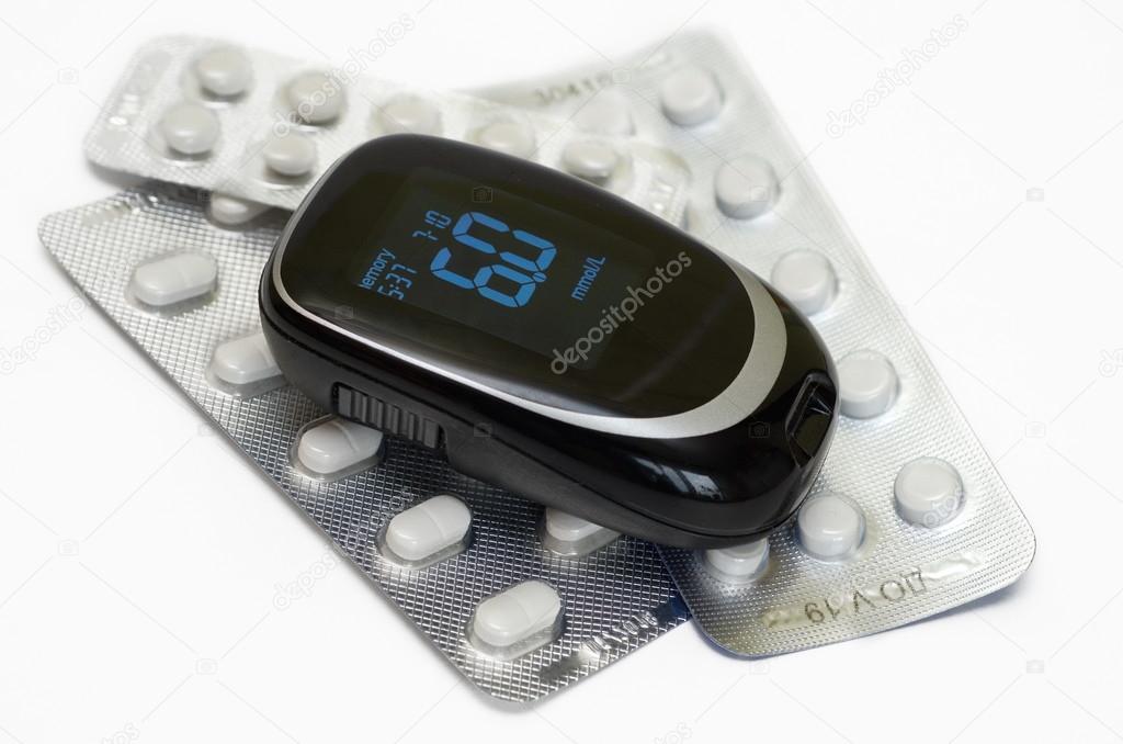 Medical blood glucose meter and pills on white background