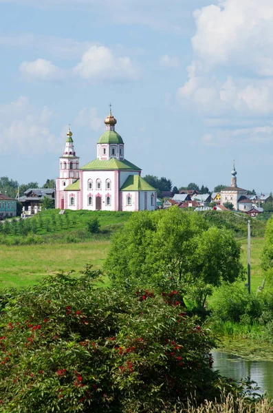 Summer view of the Church of Elijah the Prophet on the banks of the Kamenka river and the temple of the Tikhvin icon of the mother of God. City of Suzdal, Vladimir region. Golden ring of Russia