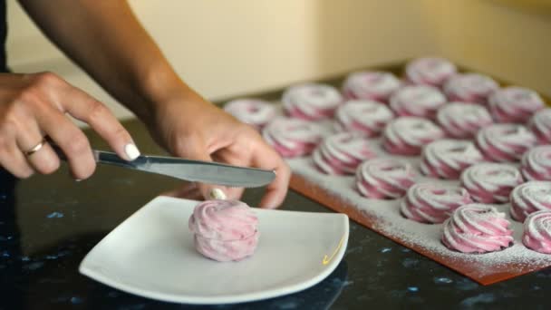 Young woman cuts marshmallow with knife in kitchen of apartment indoors. — Stock Video