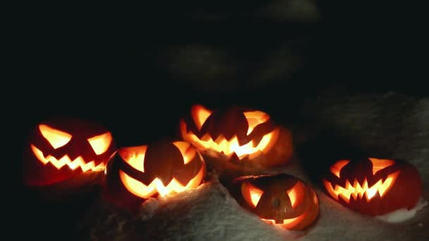 Calabazas de Halloween en la noche nevada de invierno con fantasmas sobrevolando. Con bucle — Vídeo de stock