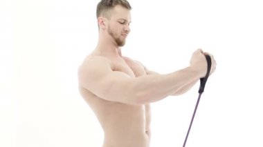 Beyaz zemin üzerinde bir direniş band ile kol egzersizleri yapıyor kaslı bir vücut geliştirmeci orta çekim