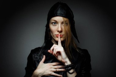 genç kadın kırmızı tüyler sessiz olmak için el hareketi ile koyu arka planda sessizlik işareti gösterir