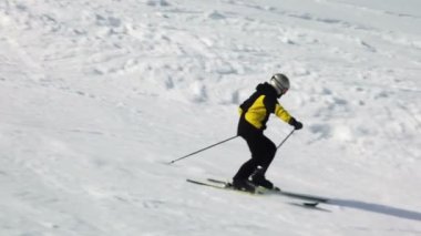 Genç yetişkin kayakçı soğuk kışta huzurlu ve mükemmel havanın tadını çıkarıyor. Kayak merkezindeki mükemmel hazırlanmış kayak pistinde tek başına kayak yapmak