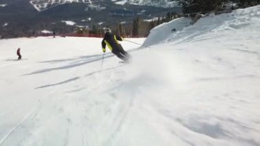 Genç yetişkin kayakçı soğuk kışta huzurlu ve mükemmel havanın tadını çıkarıyor. Kayak merkezindeki mükemmel hazırlanmış kayak pistinde tek başına kayak yapmak