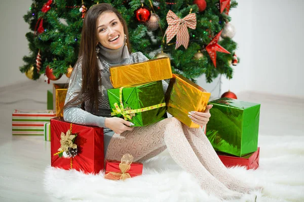 Porträtt av glad ung kvinna julklapp lådor framför granen Royaltyfria Stockfoton
