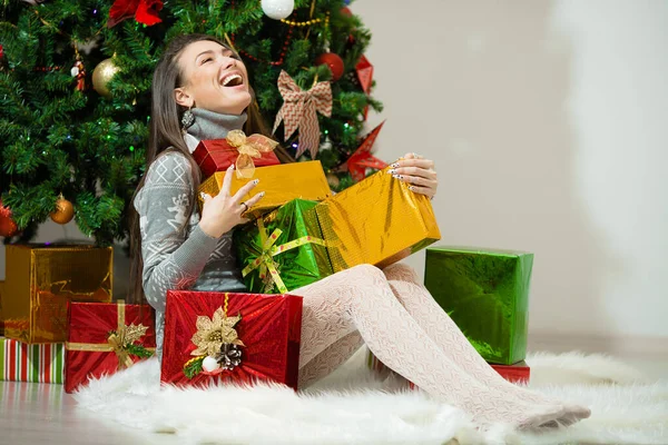 Porträtt av glad ung kvinna julklapp lådor framför granen Stockbild