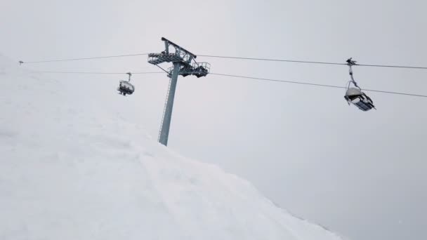 Przenoszenie stacji wyciągu krzesełkowego na szczycie góry w pochmurny zimowy dzień — Wideo stockowe