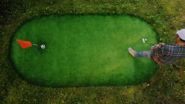 Golfer speelt een mini-veld bezaaid. Geschoten vanaf de top — Stockvideo