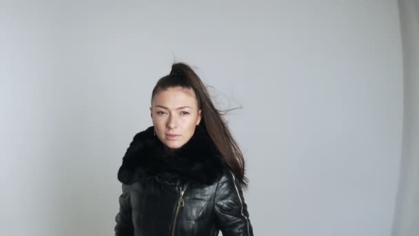 Γυναίκα με μακριά μαλλιά στον άνεμο σε κάτω σακάκι ποζάρουν στο στούντιο σε λευκό φόντο — Αρχείο Βίντεο