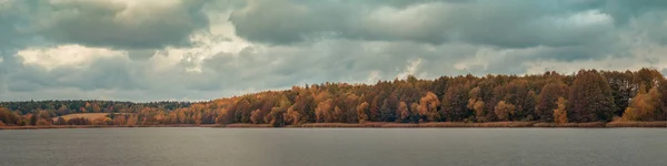 Colores de finales del otoño. Amplia vista panorámica de la orilla opuesta del río con bosques costeros bajo un cielo nublado en un día nublado de octubre. paisaje de otoño colorido —  Fotos de Stock