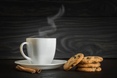 Bir fincan kahve ya da çay buharlı ve kurabiyeli doğal gri ahşap arka planda