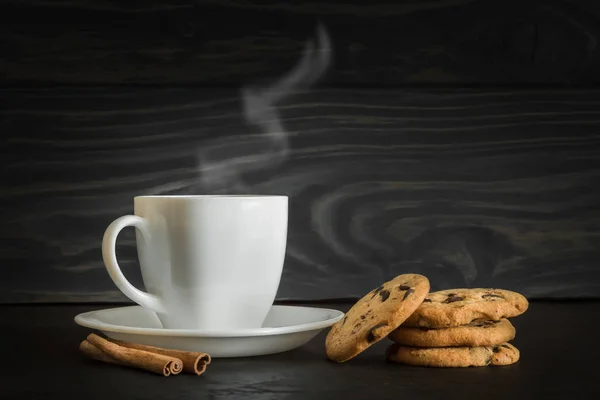 Taza de café o té con vapor y galletas sobre un fondo de madera gris natural Imagen de archivo