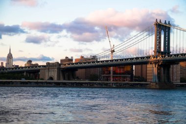 Manhattan Köprüsü ve bulutlu gökyüzü günbatımı, New York ile şehir