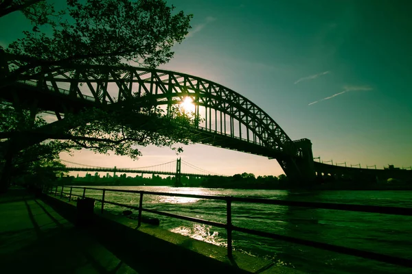 The Hell Gate Bridge and Triborough bridge over the river with walkway and the sun in dark green vintage style, New York — Stock Photo, Image