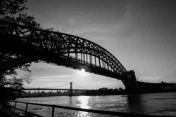 The Hell Gate Bridge e il sole si riflettono sul fiume in bianco e nero, New York — Foto Stock