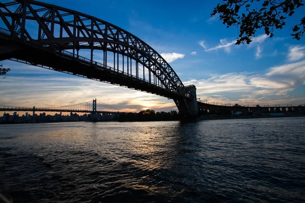 Silhuetten av Hell Gate Bridge och Triboroughen överbryggar över floden, New York — Stockfoto