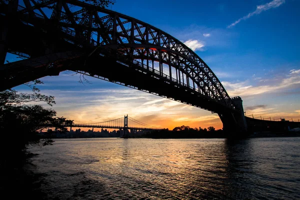 Silhouette der Höllentorbrücke und der Triborough-Brücke über den Fluss vor Sonnenuntergang, New York — Stockfoto