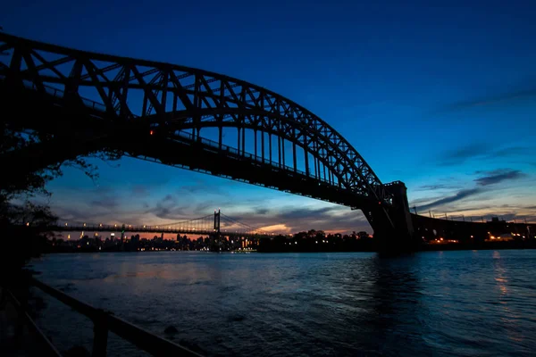 Silhueta da ponte do portão do inferno e ponte de Triborough sobre o rio antes do por do sol, New York — Fotografia de Stock