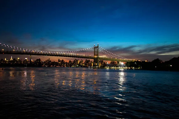 Puente de Triborough sobre el río reflectante y los edificios por la noche, Nueva York — Foto de Stock