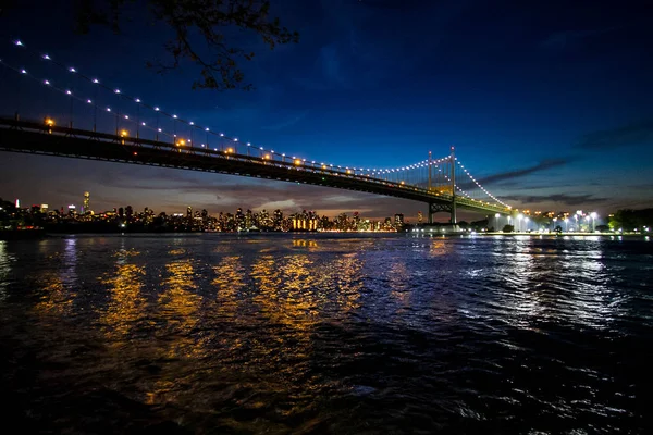 Triborough most přes reflexní řeky a budovy v noci, New York — Stock fotografie