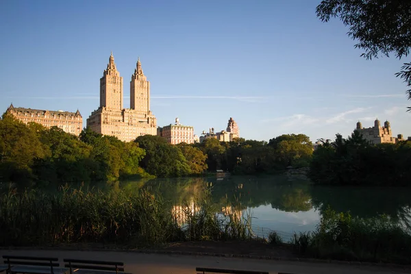 Edificios en Manhattan con lago, pasarela y cielo azul en Central Park — Foto de Stock