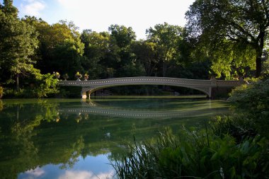 Central Park 'ta yansıtıcı sakince göl üzerinde Bow Köprüsü