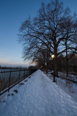 Kar yolu ve gün batımı ile göl yanındaki elektrik direğine