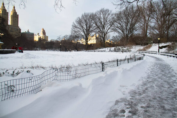 Road and snow at Central Park and buildings with sunset sky