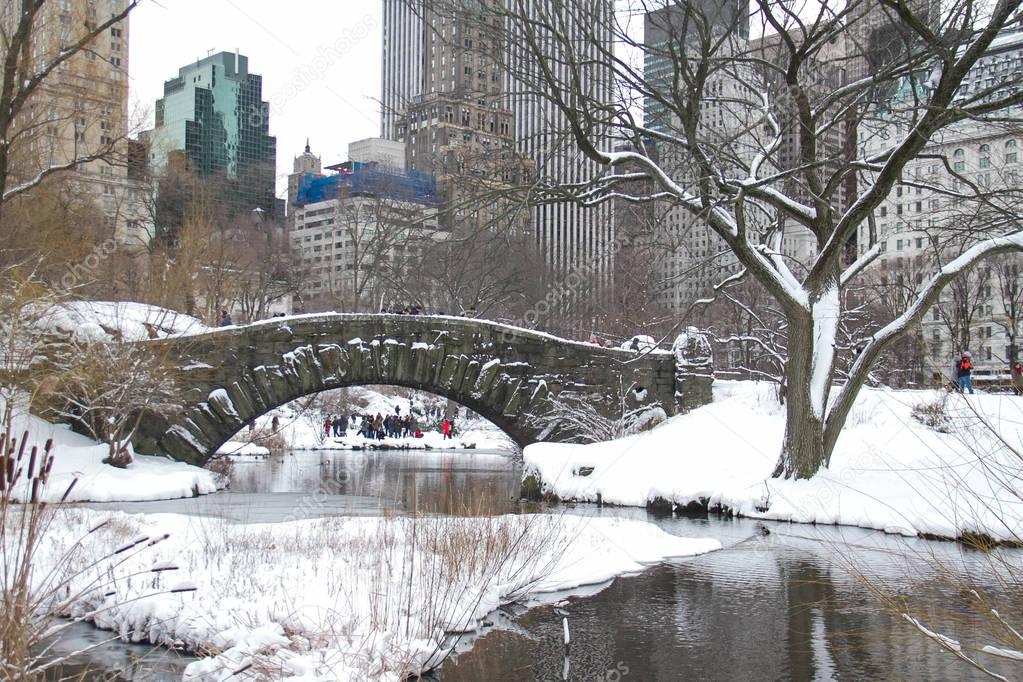 Buildings and Gapstow bridge over the icy lake and snow at Central Park