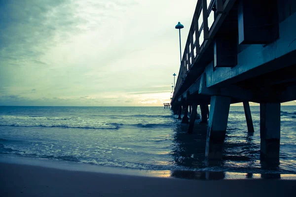 Molo sulla spiaggia con cielo nuvoloso in stile vintage — Foto Stock