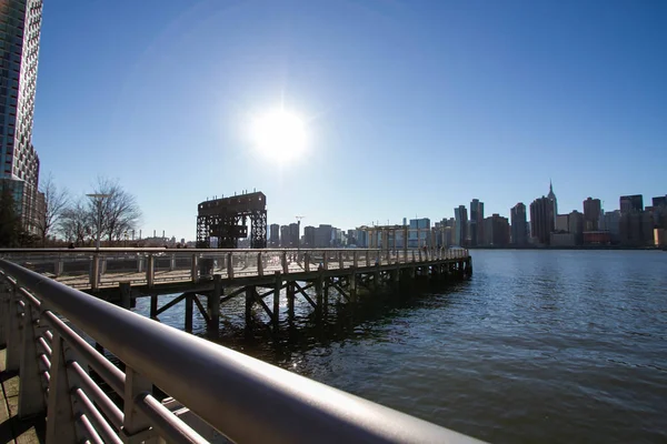 Iconic gantries of Gantry State Park and fence of pier opposite city with blue sky, New York — Stock Photo, Image