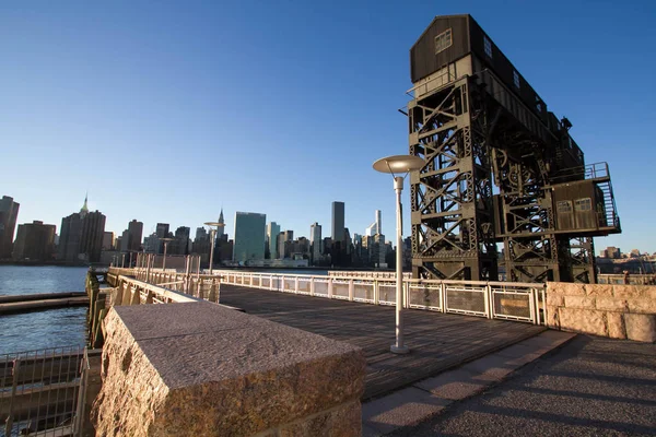 Transfiera puentes, pórticos de apoyo y muelles en el Parque Estatal Gantry Plaza y edificios en Manhattan antes del atardecer —  Fotos de Stock