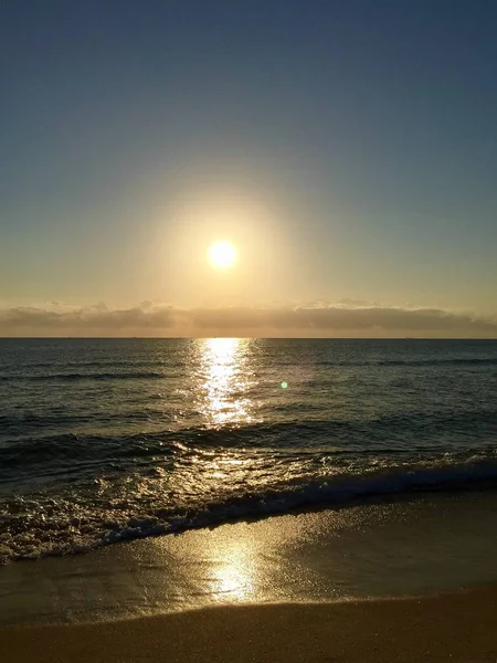 Le lever du soleil se reflète sur la plage sombre le matin — Photo