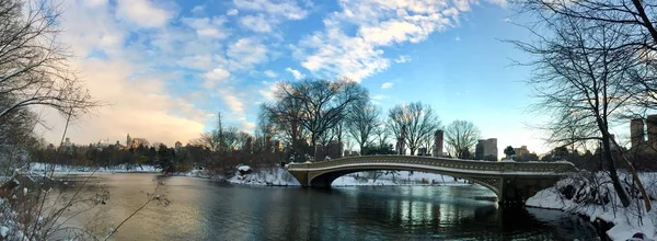 Bow bridge over the lake and snow before sunset in panorama view, Central Park, New York