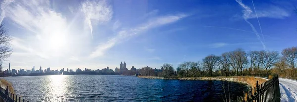 Озеро в Центральном парке и здания в Манхэттене под солнцем в панораме — стоковое фото