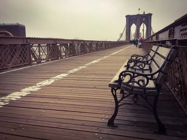 Banco de madera en la pasarela en el puente de Brooklyn y la niebla en estilo vintage oscuro — Foto de Stock