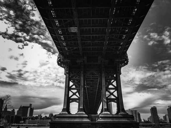 Struktura pod Manhattan bridge i miasto z pochmurnego nieba w czerni i bieli — Zdjęcie stockowe