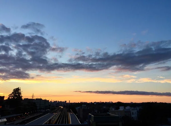 クラウドと鉄道と日没の空と街並み — ストック写真