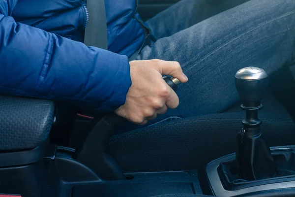 Молодой водитель дергает за ручной тормоз в машине — стоковое фото