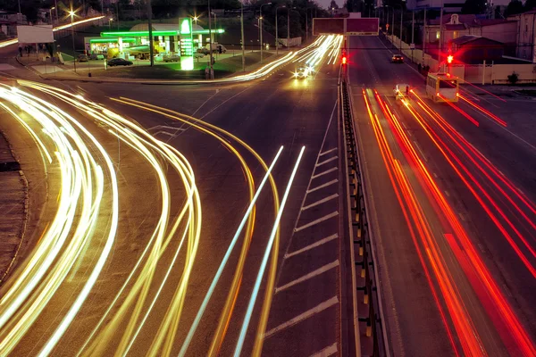 Strade cittadine e auto in movimento con luce sfocata attraverso — Foto Stock