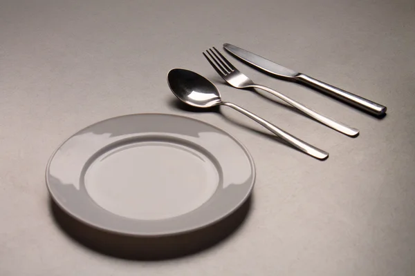 Üres tányér kanállal, késsel és villával — Stock Fotó