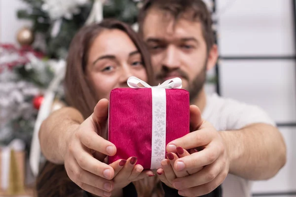 Hands of happy couple giving a Christmas gift