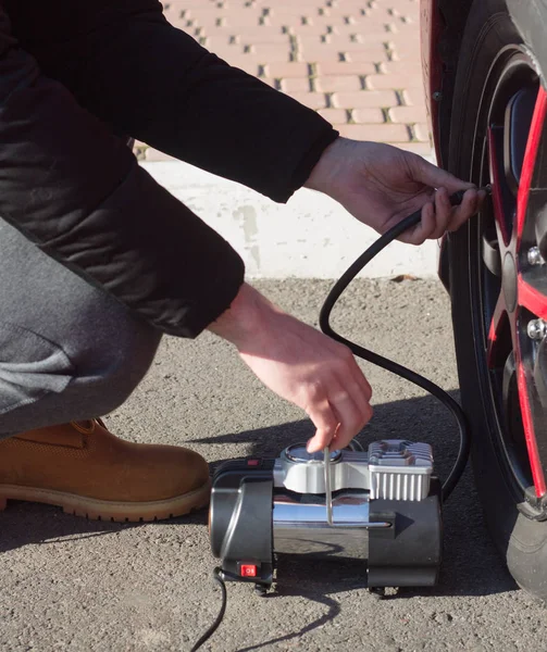 Чоловік перевіряє тиск повітря і заповнює повітря в шинах автомобіля — стокове фото