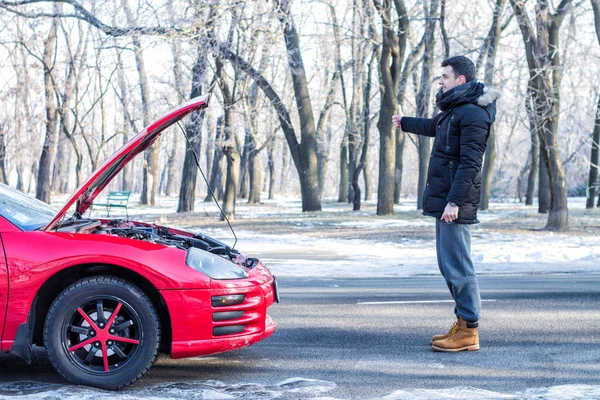 Людина сигналізує про проблеми з машиною на зимовій дорозі . — стокове фото